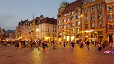 WROCLAW - POLAND - 21 Temmuz 2022: Wroclaw merkez pazar meydanı eski renkli evler, sokak lambası ve akşam vakti turistleri gezdiren insanlar. Avrupa.