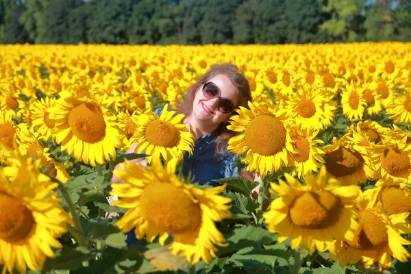 Portrait of a young smiling woman in sunflowers.