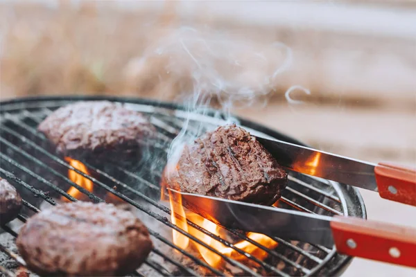 Closeup Photo of a Tasty Juicy Patty for Burgers Cooked on Grill on Open Fire. Traditional Delicious Food. USA Independance Day. Outdoors Family Party.