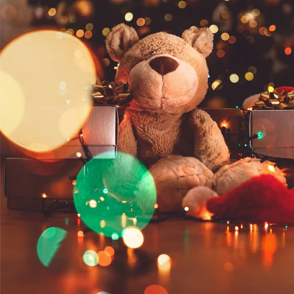 漂亮柔软的熊玩具坐在美丽的节日圣诞树旁 装饰着色彩艳丽的加兰 家居舒适的寒假 — 图库照片