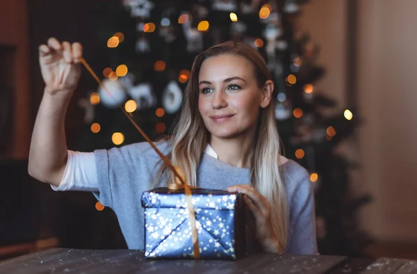 在装饰过的圣诞树背景下 一个可爱的女孩在家里打开节日礼品盒的肖像 寒假快乐 欢度佳节 — 图库照片