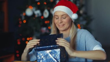 FHD 'nin Noel arifesinde Mutlu Bir Kızın Evde Hediye Tadını Çıkartan Portresi videosu. Madalyalı Xmas Bokeh Ağacı Arkaplanı. - Mutlu yıllar. Kış tatilleri. 1920x1080