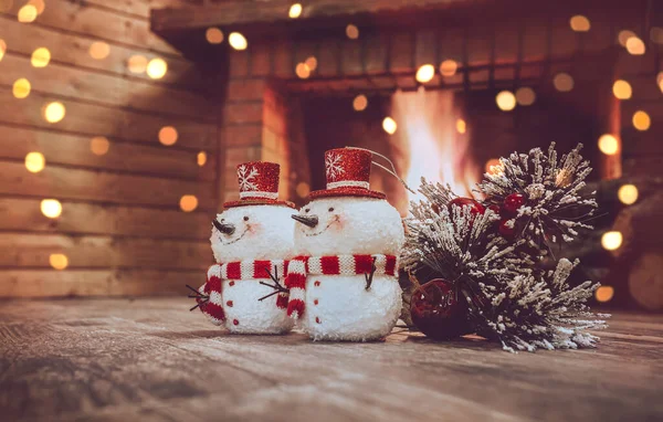 冬の家のお祭り騒ぎフェストゥーンで飾られた 暖炉の近くの2つの小さな雪だるまと松の木の枝 家庭での平和なクリスマスの夜 — ストック写真