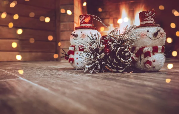Christmas Home Decor. Winter House Decorated with Festoon. Two Little Snowman and Pine Tree Branch Near Fireplace. Photo with Copy Space.