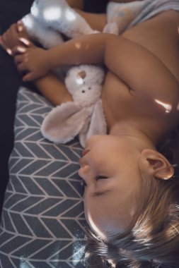 Beautiful child is asleep in the babys room. Portrait of a healthy pretty kid enjoying sweet dreams with his favorite soft toy rabbit.