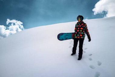 Active people enjoying the snow. Sports life and leisure. Snowboarder tourist girl walking on the mountain top. Ski park resort. Winter holidays and seasonal vacation travel.
