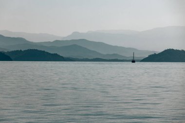 Dağların ve deniz manzarasının fotoğrafı. Hava bulutlu. Yelkenliyle seyahat et. Denizde yaz tatili. Türkiye