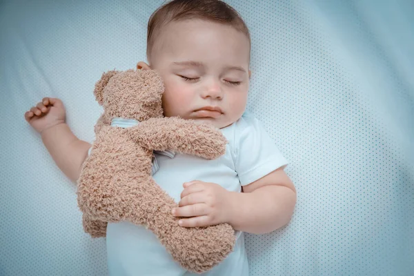 一个可爱的小男孩和一只柔软的玩具熊在婴儿床里打盹的合影 睡个好觉健康的家庭生活 — 图库照片