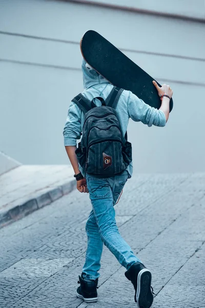 バックパックを手にスケートボードと歩いてティーンエイジャーの裏側 屋外で活発な少年 若い人たちの幸せな時間 スポーツライフスタイル — ストック写真