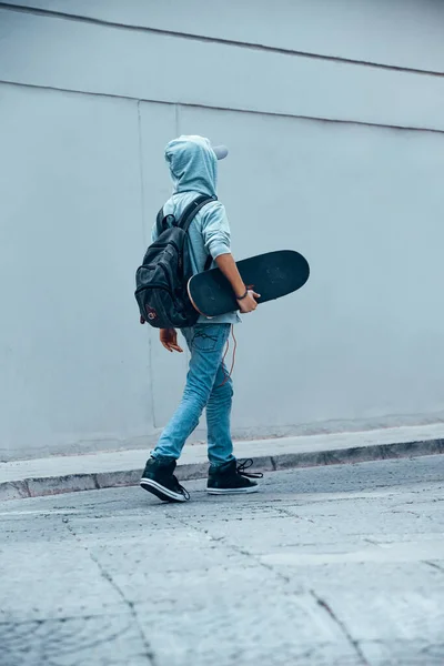 バックパックを手にスケートボードと歩いてティーンエイジャーの裏側 屋外で活発な少年 若い人たちの幸せな時間 スポーツライフスタイル — ストック写真