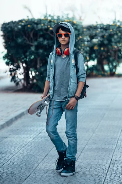 屋外で楽しんで手にスケートボードとハンサムなアクティブな十代の少年の肖像画 若者の情熱 青年期のスポーツ生活 — ストック写真