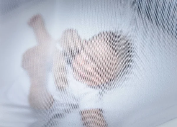 一张有选择的焦点照片 是一个可爱的小孩睡在婴儿床里 在白色柔和的树冠下 带着柔软的玩具熊 在家里过平静的生活 — 图库照片