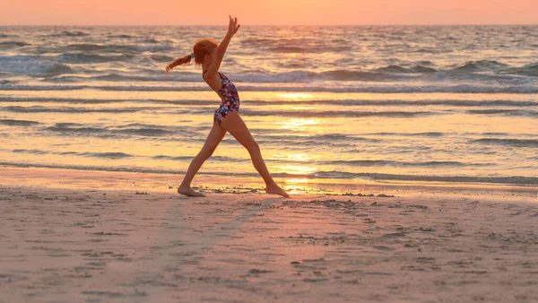 夕日の空を背景にビーチでスポーツの練習をしているかなり10代の女の子 積極的な夏のキャンプ 海の近くで踊る 健康な子供時代 — ストック写真