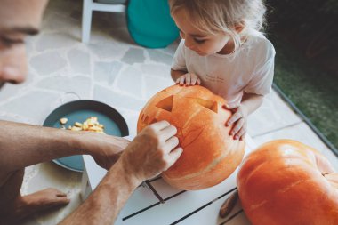 Baba ve küçük oğlu Cadılar Bayramı partisi için balkabağı oyuyor. Evi dekore ediyorum. Geleneksel sonbahar Amerikan korku bayramı.