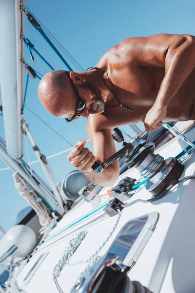 Handsome sailor working on sailboat. Enjoying travel along the sea. Yachting sport. Summer holidays on the water.