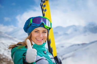 Aktif bir kızın portresi kış kayak merkezinde eğleniyor. Güzel bir bayan sporcu kıyafeti ve kayak maskesi giyiyor. Parmakla işaret ediyor. Keyfi yerine geliyor.