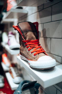 Eskici dükkanının rafında kırmızı ayakkabı bağcığı olan havalı kahverengi ayakkabılar. Her gün moda. Sıradan botlar. Ayakkabı dükkanı.