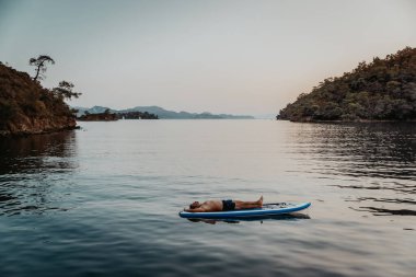 Sakin erkek, yaz tatilini dağların arasında denizde geçiriyor. Yemek yerken meditasyon yap. Bu güzel durgun yerde sallanan sportif bir adam..