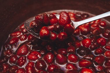 Kırmızı çilek reçeli arka planı. Ev yapımı çilek reçeli ilerleme kaydediyor, kaynıyor. Konserve için taze olgun böğürtlen pişiriyorum. Organik tatlılar, tatlı..