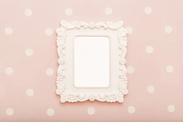 stock image Beautiful stylish figured square white frame for childrens photo hangs on soft pink wall decorated with small dots in childrens bedroom.