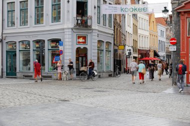 Bruges, Belçika - 7 Eylül 2022: kaldırımlı caddelerin kesiştiği köşedeki bina. Bu binanın zemin katında bir dükkan penceresi var. Yakınlarda birkaç kişi var.