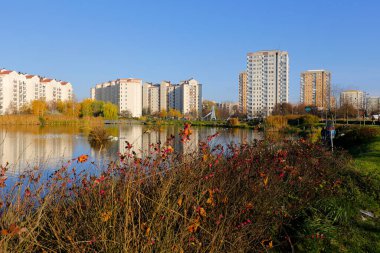 Varşova, Polonya - 6 Kasım 2022: Praga Poludnie bölgesinde geniş bir parka ve oldukça büyük bir göle bitişik çok katlı binalar.