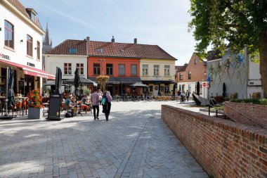 Bruges, Belçika - 12 Eylül 2022: Açık hava restoranları olan evler. Birçok sandalye ve masa binaların yanındaki kaldırımda bulunmaktadır..