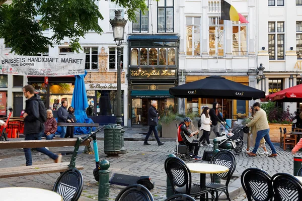 Brussels, Belgium - September 16, 2022: Street scene in the old town district. There are facades of buildings, shop windows, outdoor cafes, someone plays the guitar, there are other people walkin