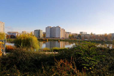 Varşova, Polonya - 6 Kasım 2022: Praga Poludnie bölgesinde geniş bir parka ve oldukça büyük bir göle bitişik çok katlı binalar.