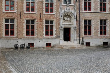 Bruges, Belgium - September 9, 2022: The large brick building of the Gruuthuse museum with red window frames is on a large paved square. There is an ornate doorway into the building