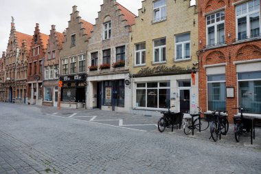 Bruges, Belgium - September 13, 2022: A row of traditional brick houses on a cobbled street with a designated parking spot, most likely for the needs of the small hotel visible here