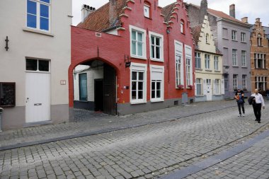 Bruges, Belgium - September 11, 2022: Residential houses are visible along a narrow cobbled street in the old part of town. There aren't many people on the street here