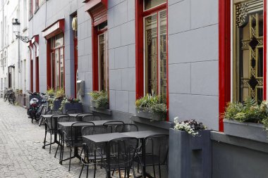 Bruges, Belgium - September 8, 2022: The windows of the restaurant, in front of which tables and chairs were placed on the sidewalk waiting for guest