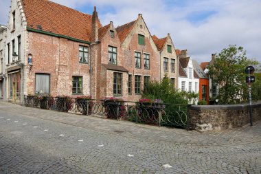 Bruges, Belgium - September 13, 2022: Residential buildings are behind a small bridge that is visible right next to the houses. It is located at a narrow intersection of cobblestone streets