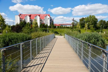 Warsaw, Poland - August 7, 2022: Narrow footbridge over the water in the Goclaw estate, in the Praga Poludnie district, is the way to the church, visible a bit further