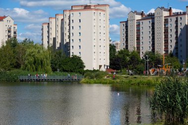 Warsaw, Poland - August 7, 2022: Overall view of multi-storey residential buildings by a park and a lake in the Goclaw housing estate, in the Praga Poludnie district.