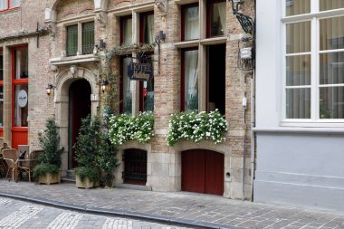 Bruges, Belgium - September 13, 2022: There is a brick facade of the house by the cobblestone walkway. There is also an entrance door to the hotel located in this buildin