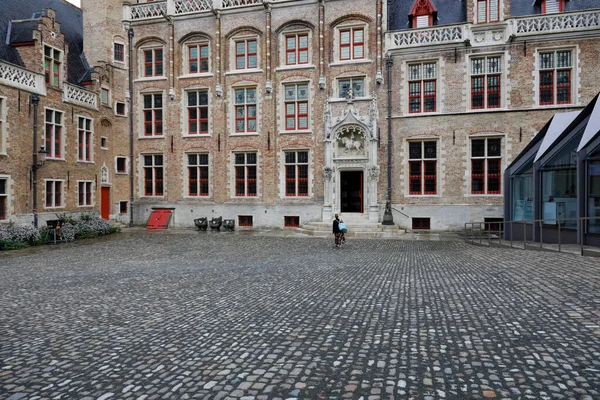 Bruges, Belgium - September 9, 2022: The large brick building of the Gruuthuse museum with red window frames is on a large paved square. There is an ornate doorway into the buildin