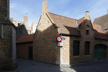 Bruges, Belçika - 12 Eylül 2022: Eski kentin dar ve kaldırımlı caddelerinin kesiştiği yerdeki tuğla binalar. Bu güneşli günde burada kimse yok.