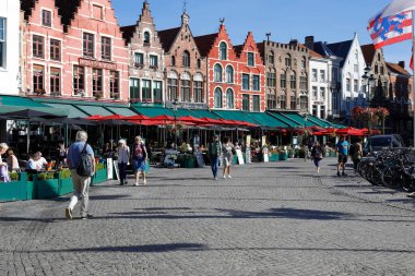 Bruges, Belçika - 12 Eylül 2022: Renkli, açık hava restoranları olan tuğlalı evler. Şehrin en büyük meydanı, yayaları özgürce dolaşmak için tasarlandı.