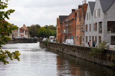 Bruges, Belçika - 10 Eylül 2022: Bina sırası oldukça geniş bir kanal boyunca yer almaktadır. Bu suyun her iki tarafında dar sokaklar görülebilir.