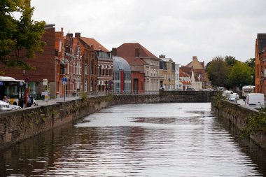 Bruges, Belçika - 10 Eylül 2022: Bina sırası oldukça geniş bir kanal boyunca yer almaktadır. Bu su yolunun her iki tarafında dar sokaklar görülebilir.