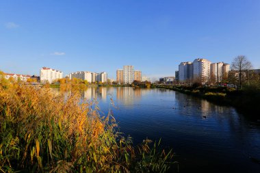 Varşova, Polonya - 6 Kasım 2022: Praga Poludnie bölgesinde geniş bir parka ve oldukça büyük bir göle bitişik çok katlı binalar.