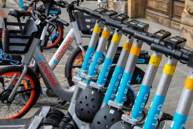 Florence, İtalya - 15 Nisan 2023: Kick-scooter 'lar ve bisikletler kaldırımdaki park yerine park edilmişti. Elektrikli scooterlar şu anda popüler bir ulaşım aracı..