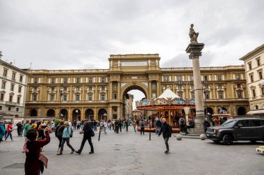 Floransa, İtalya - 13 Nisan 2023: Kemerli kapılı bir bina Piazza della 'nın ön cephesini oluşturur. Atlıkarıncanın çalıştığı bu meydan, turistler ve yerel halk tarafından sık sık ziyaret ediliyor.