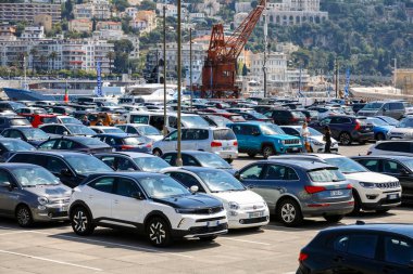 Güzel, Fransa - 23 Nisan 2023: limanın yanında büyük bir otopark ve bir sürü araba var. Tepenin biraz yukarısında bir apartman var.