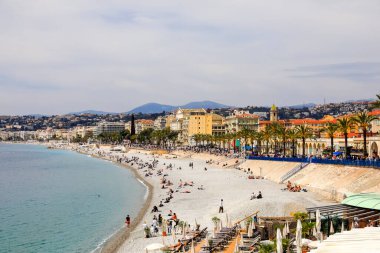 Güzel, Fransa - 22 Nisan 2023: Bulutlu güne rağmen insanların bulunduğu deniz kıyısı, binalar ve plaj manzarası