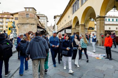 Floransa, İtalya - 14 Nisan 2023: Bir grup turist Arno Nehri boyunca uzanan ünlü ortaçağ Ponte Vecchio 'sunu (Eski Köprü) görüyor