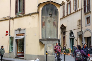 Floransa, İtalya - 17 Nisan 2023: Floransa 'nın tarihi merkezinde eski şehrin dar sokakları arasındaki bir binanın köşesinde eski bir tapınak yer almaktadır.