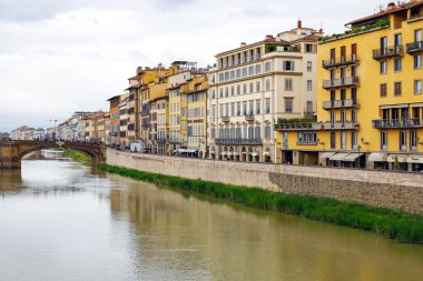 Floransa, İtalya - 14 Nisan 2023: Arno Nehri kıyısındaki eski kasabada bir dizi apartman dairesi. Arno Nehri 'ni geçen köprü biraz ileride görünüyor.